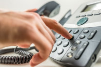 Zeigefinger drückt auf Taste eines Telefons
